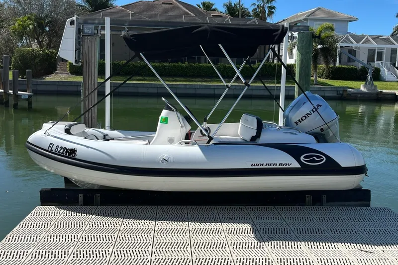 Slide: The Image of 2020 Walker Bay Generation 360 boat with Honda motor docked by waterfront homes. - 2