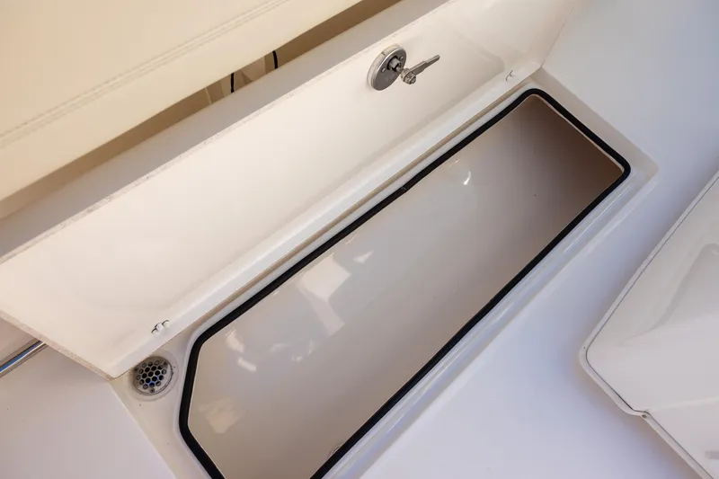 Slide: The Image of 2022 Cobia 320 Center Console storage compartment with open lid and drain. - 13