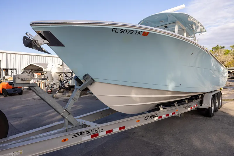 Slide: The Image of 2022 Cobia 320 Center Console boat on trailer in a marina setting. - 2