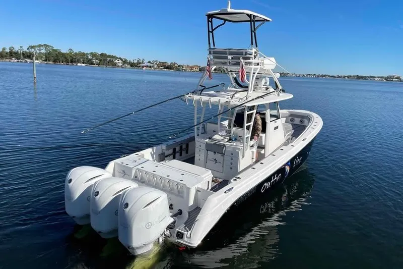 Slide: The Image of 2013 Everglades 355 Center Console boat on calm water, featuring triple outboard engines. - 3