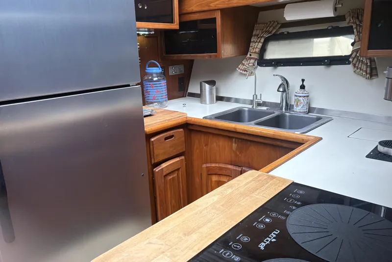 Slide: The Image of 1987 Californian 53 Cockpit Motor Yacht kitchen with stainless steel fridge and dual sinks. - 6