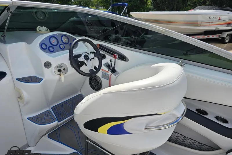 Slide: The Image of Interior of a 2005 Baja 275 boat featuring a sleek dashboard and white seating. - 51