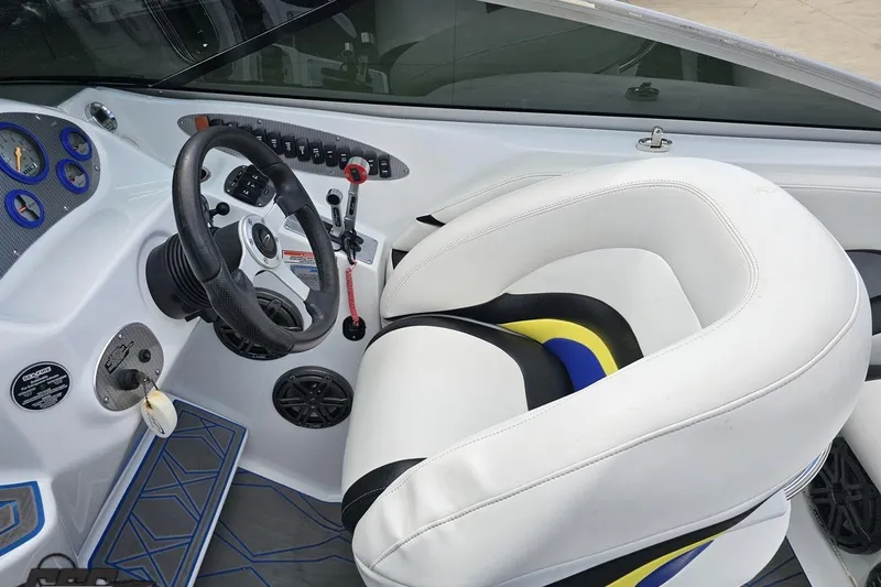 Slide: The Image of 2005 Baja 275 boat cockpit with steering wheel, gauges, and white cushioned seat. - 64