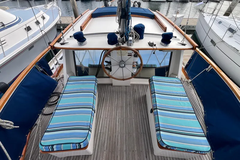 Slide: The Image of 1986 Nauticat 33' sailboat cockpit with striped cushions and wooden steering wheel. - 17