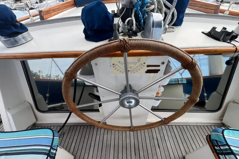Slide: The Image of 1986 Nauticat 33' sailboat helm with wooden wheel and nautical equipment. - 18