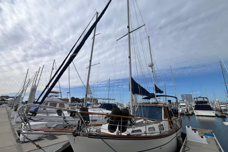 Slide: The Image of 1986 Nauticat 33' sailboat docked at a marina under a cloudy sky. - 2