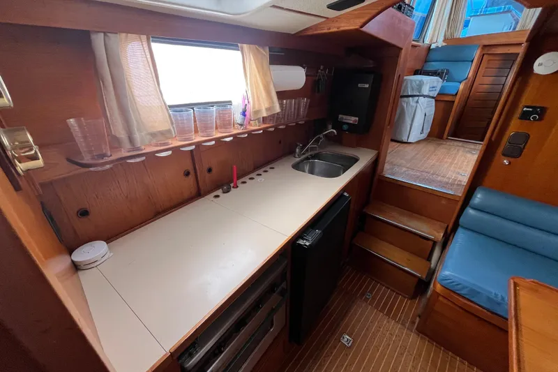 Slide: The Image of Interior of 1986 Nauticat 33' yacht featuring a compact kitchen with sink and seating area. - 42