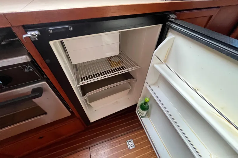Slide: The Image of Open refrigerator in 1986 Nauticat 33' yacht galley, showing interior shelves and wooden flooring. - 47