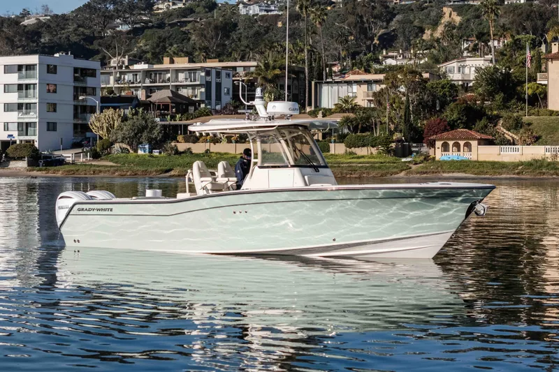 Slide: The Image of 2022 Grady-White Canyon 306 boat on calm water near residential shoreline. - 2