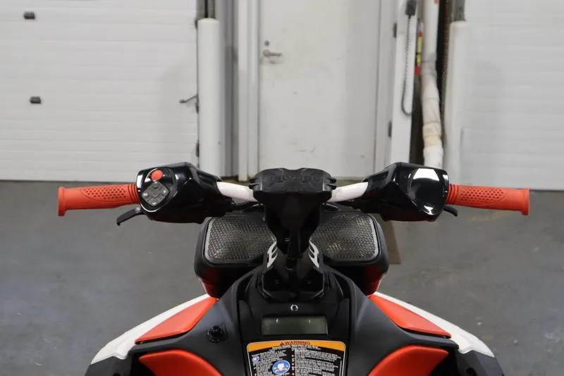 Slide: The Image of 2025 Sea-Doo Spark Trixx handlebars with red grips in a garage setting. - 10