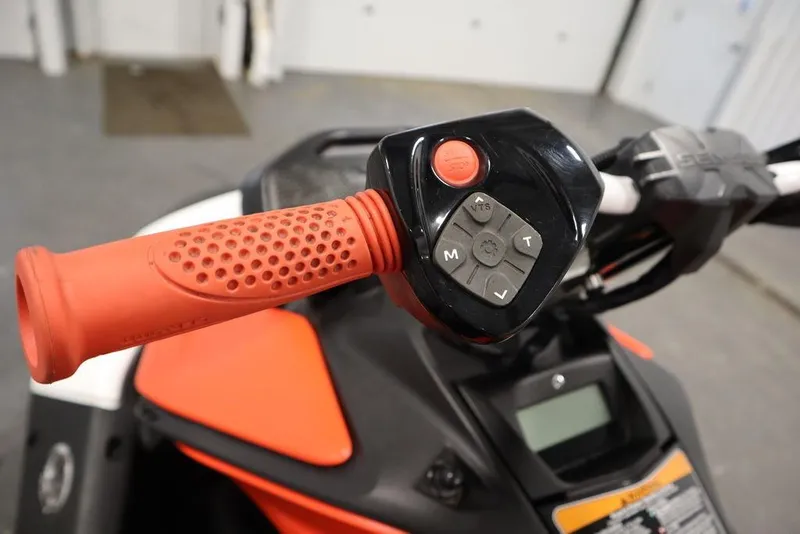 Slide: The Image of 2025 Sea-Doo Spark Trixx handlebar controls with vibrant red grip and buttons. - 11