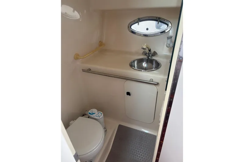 Slide: The Image of 1998 Tiara Yachts 2900 Coronet bathroom with sink, toilet, and porthole window. - 31