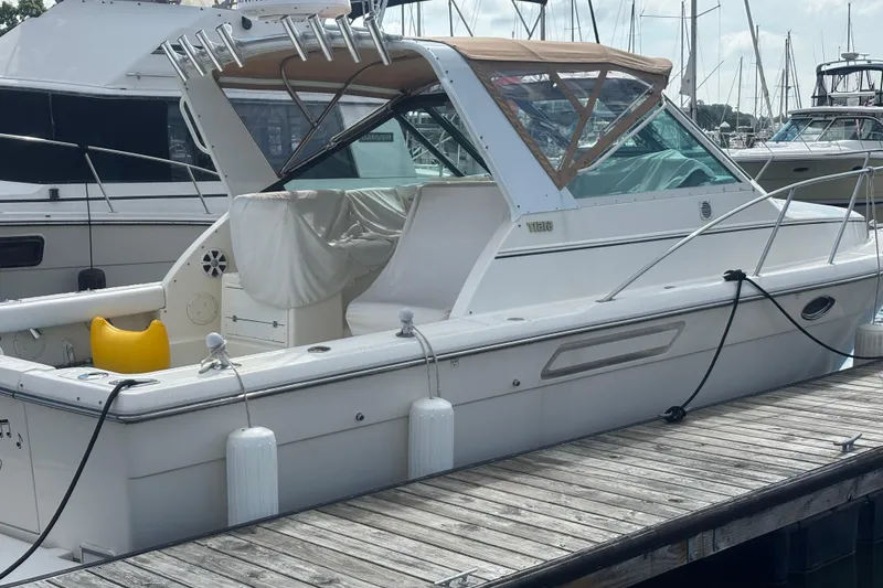 Slide: The Image of 1998 Tiara Yachts 2900 Coronet docked at marina, featuring white exterior and tan canopy. - 8
