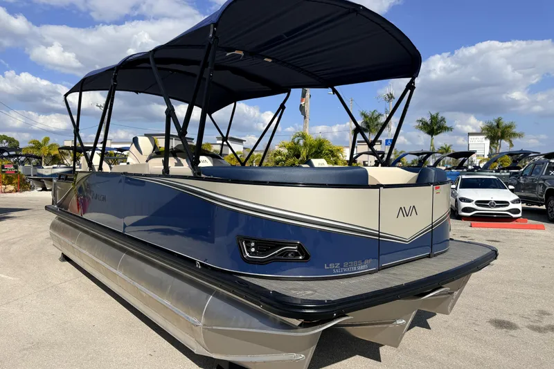Slide: The Image of 2026 Avalon LSZ Rear Fish 24' pontoon boat with canopy, parked outdoors under a blue sky. - 5