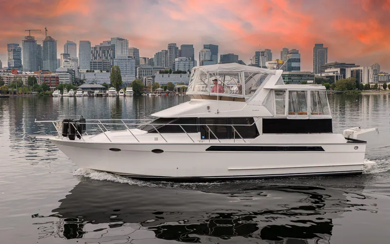 The Image of 1991 Ocean Alexander 440 Sundeck CPMY cruising near city skyline at sunset. - 0