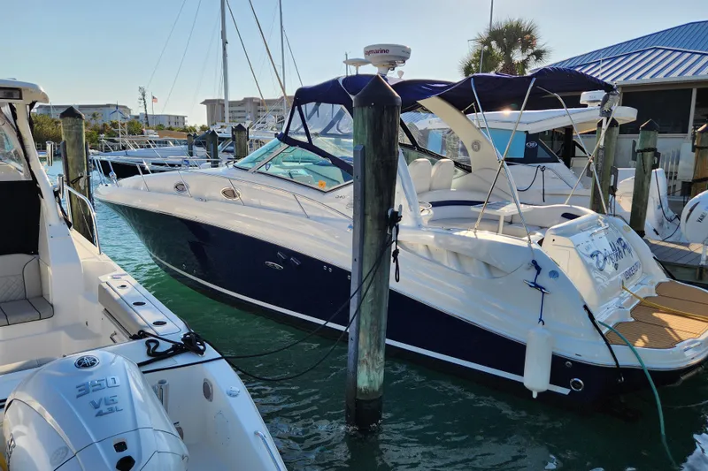 The Image of 2005 Sea Ray 340 Sundancer docked at marina, featuring sleek design and blue canopy. - 0