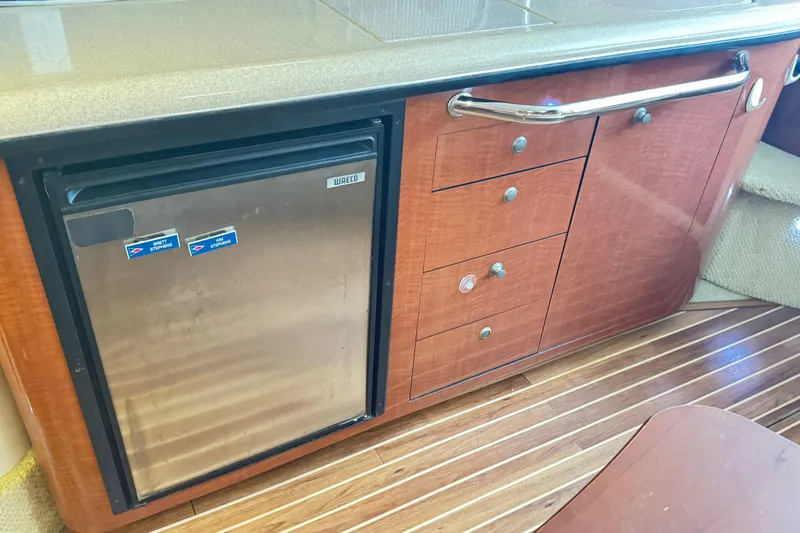 Slide: The Image of 2005 Sea Ray 340 Sundancer interior with wood cabinetry and compact fridge. - 11