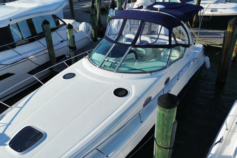 Slide: The Image of 2005 Sea Ray 340 Sundancer docked at marina, featuring sleek design and blue canopy. - 2