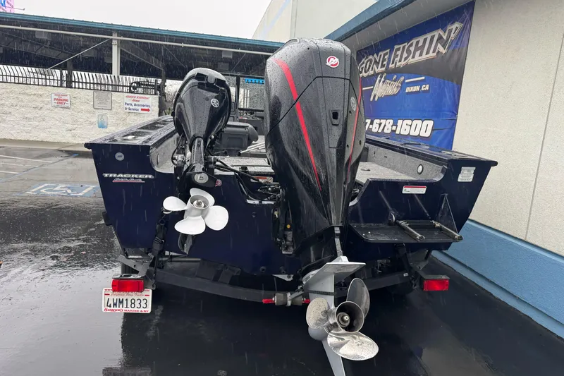 Slide: The Image of 2025 Tracker Targa V-19 WT boat with dual outboard motors in a parking lot. - 7