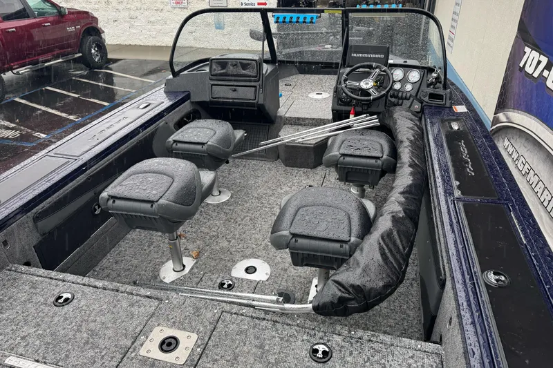 Slide: The Image of 2025 Tracker Targa V-19 WT boat interior with seating and steering console in a parking lot. - 8