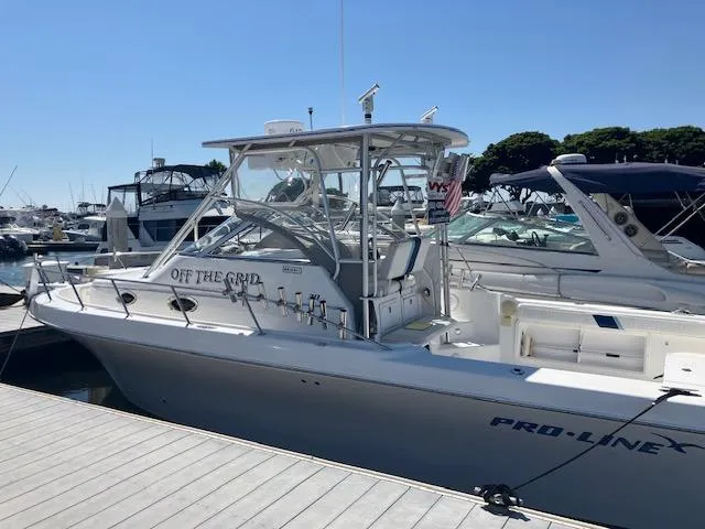 The Image of 2004 Pro-Line 30 WALK boat docked at marina, featuring sleek design and spacious deck. - 0