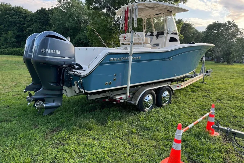 Slide: The Image of 2018 Grady-White Canyon 271 boat on trailer with Yamaha engines, parked on grass. - 2