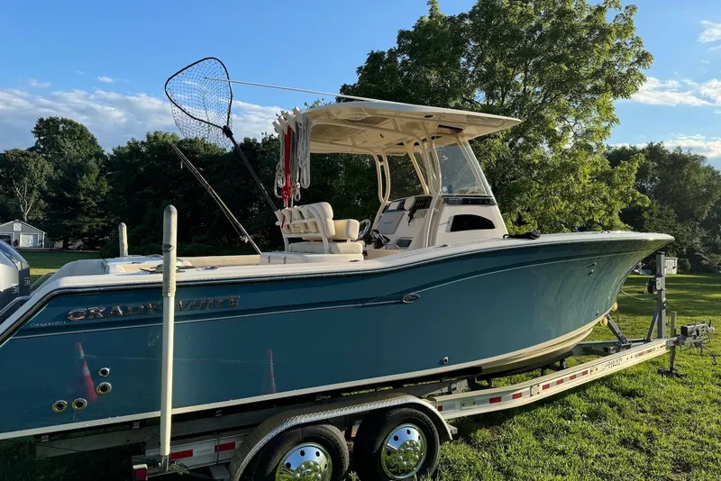 Slide: The Image of 2018 Grady-White Canyon 271 boat on trailer, surrounded by lush greenery. - 3