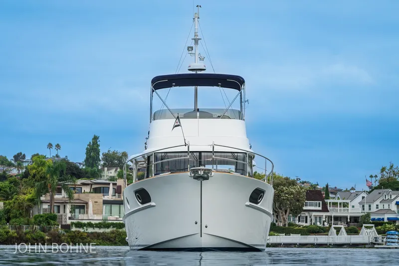 Slide: The Image of 2018 Beneteau Swift Trawler 44 yacht on calm water, with scenic coastal backdrop. - 10