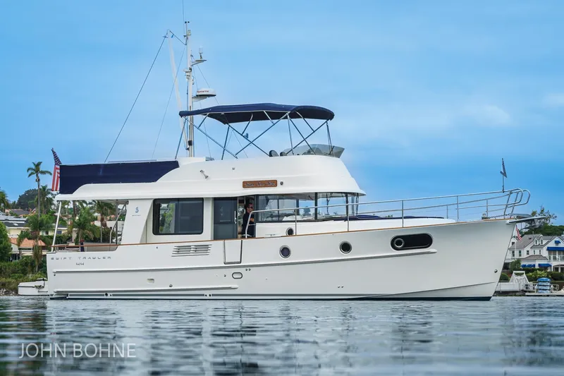 Slide: The Image of 2018 Beneteau Swift Trawler 44 on calm water, showcasing elegant design and spacious deck. - 11