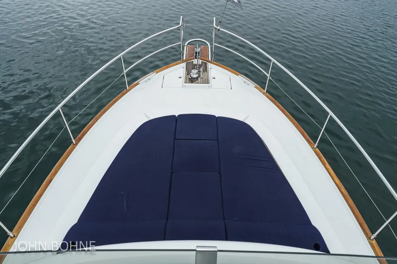 Slide: The Image of 2018 Beneteau Swift Trawler 44 bow with blue cushions on calm water. - 12