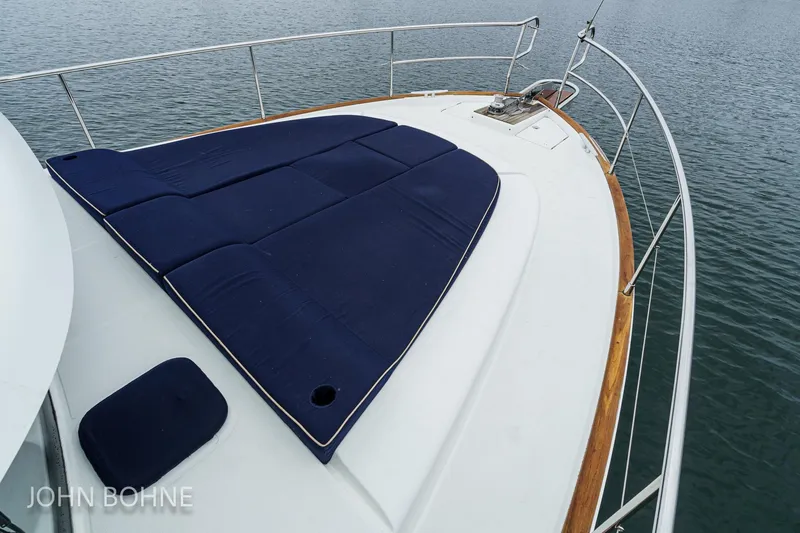 Slide: The Image of 2018 Beneteau Swift Trawler 44 bow with blue sunpad, surrounded by calm water. - 13