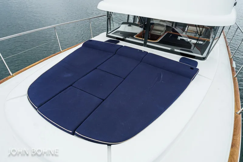 Slide: The Image of 2018 Beneteau Swift Trawler 44 with blue deck cushions, docked on calm water. - 20