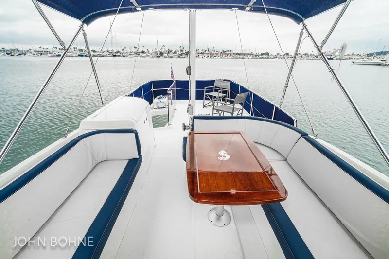 Slide: The Image of 2018 Beneteau Swift Trawler 44 flybridge with seating and table, overlooking marina. - 27