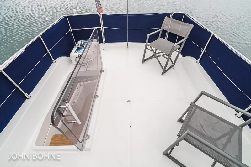 Slide: The Image of 2018 Beneteau Swift Trawler 44 deck with chairs and railing on calm water. - 30