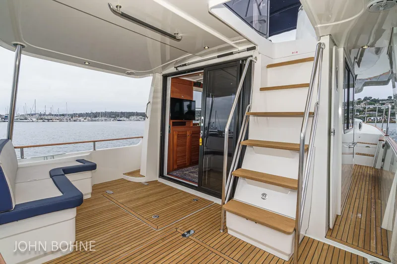 Slide: The Image of 2018 Beneteau Swift Trawler 44 interior with wooden deck, seating, and stairs. - 45