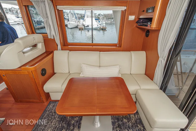 Slide: The Image of Interior of 2018 Beneteau Swift Trawler 44 with beige seating and wooden table. - 50