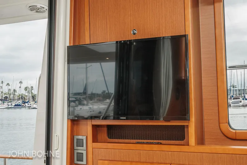 Slide: The Image of Interior of 2018 Beneteau Swift Trawler 44 with mounted TV and marina view. - 53