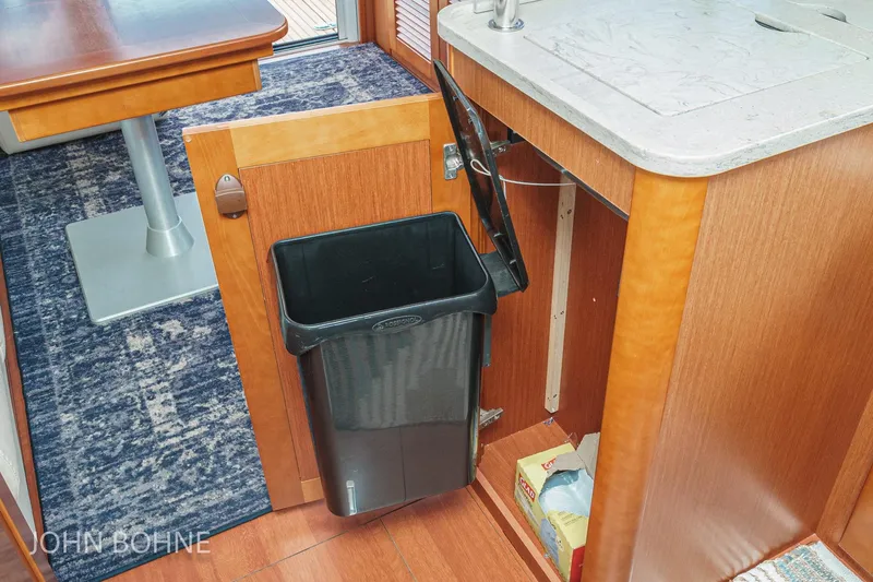 Slide: The Image of Interior of 2018 Beneteau Swift Trawler 44 with open cabinet and trash bin. - 66