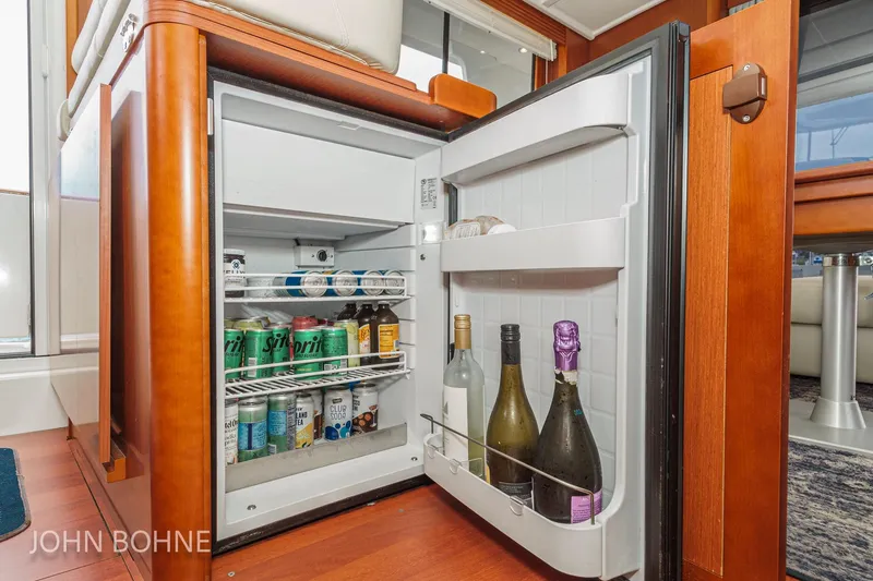 Slide: The Image of Open fridge on 2018 Beneteau Swift Trawler 44, stocked with beverages and wine bottles. - 67
