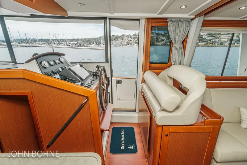Slide: The Image of Interior of 2018 Beneteau Swift Trawler 44 with helm and seating, overlooking marina. - 71