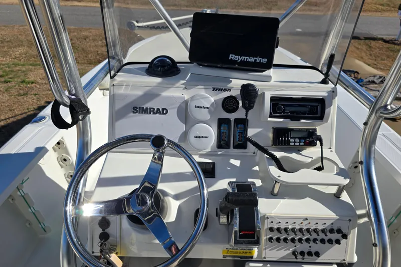 Slide: The Image of 2004 Triton 240 LTS boat console with steering wheel, Simrad and Raymarine electronics. - 13