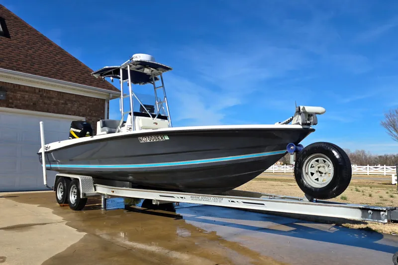 Slide: The Image of 2004 Triton 240 LTS boat on trailer, parked near a garage under clear blue sky. - 3