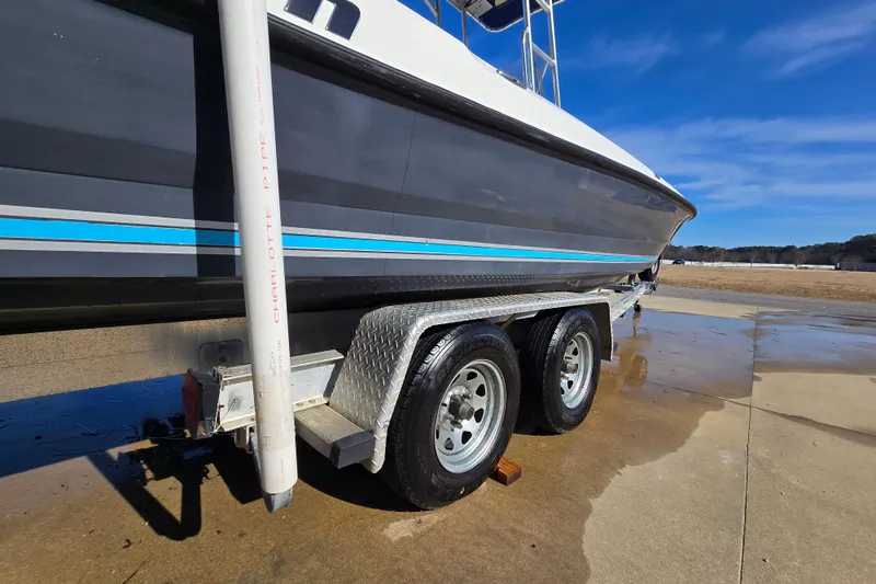 Slide: The Image of 2004 Triton 240 LTS boat on trailer, side view, with blue stripe detailing. - 6