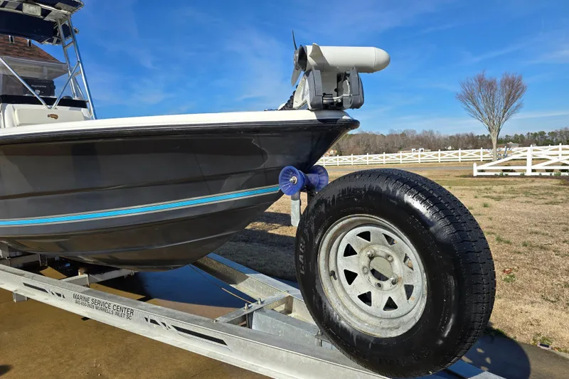 Slide: The Image of 2004 Triton 240 LTS boat on trailer, parked outdoors under clear blue sky. - 7