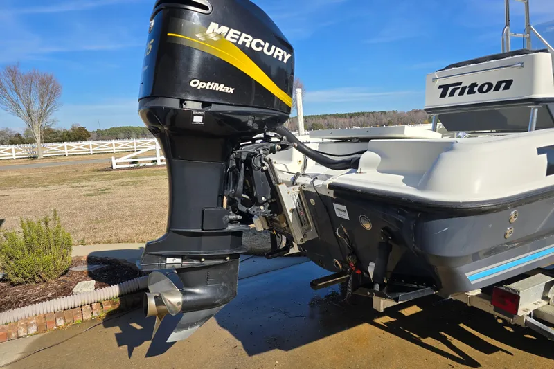 Slide: The Image of 2004 Triton 240 LTS boat with Mercury OptiMax outboard motor, parked outdoors. - 8