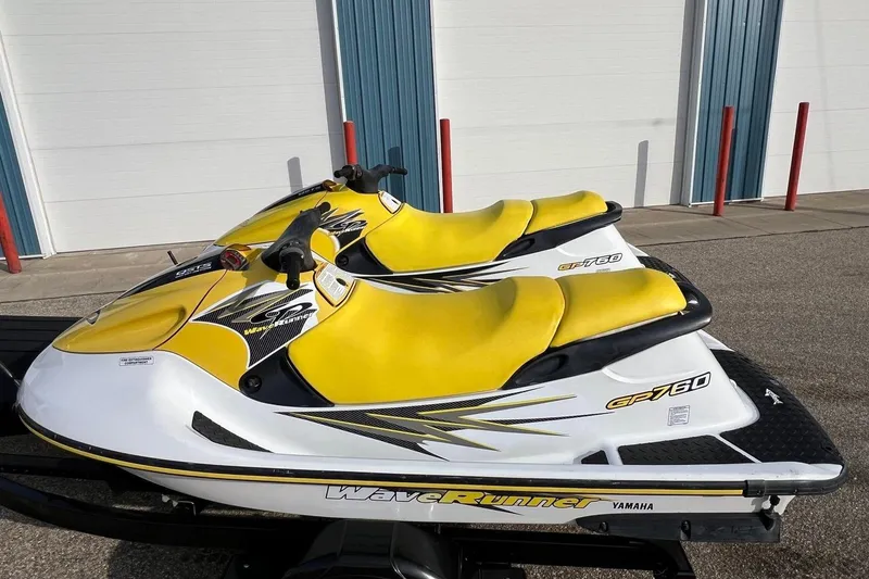 The Image of 1998 Yamaha GP760 WaveRunner with yellow seats, parked outdoors on a trailer. - 0