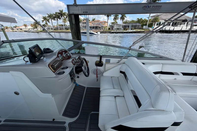 Slide: The Image of 2004 Formula 260 Bowrider boat interior with steering wheel and seating, docked by waterfront homes. - 13
