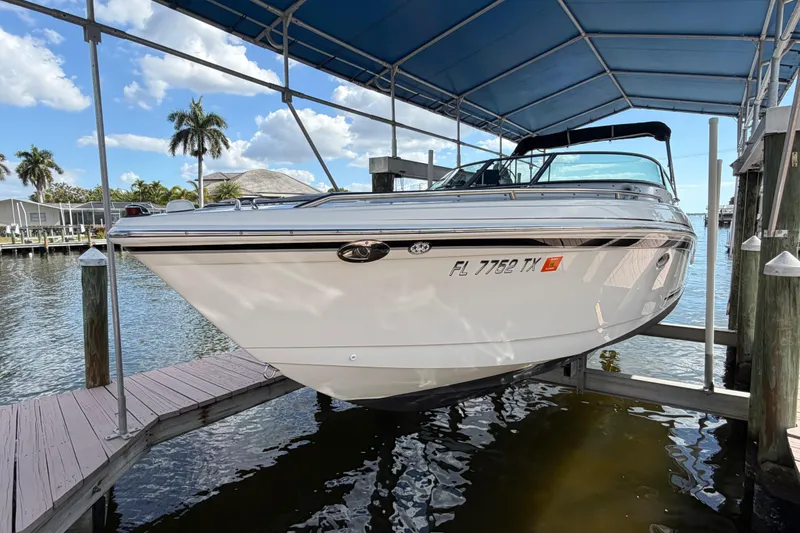 Slide: The Image of 2004 Formula 260 Bowrider boat docked under a canopy, with scenic waterfront view. - 2
