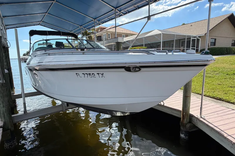 Slide: The Image of 2004 Formula 260 Bowrider boat docked under a canopy near waterfront homes. - 3