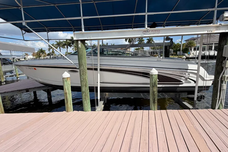 Slide: The Image of 2004 Formula 260 Bowrider boat docked under a canopy, surrounded by water and palm trees. - 7